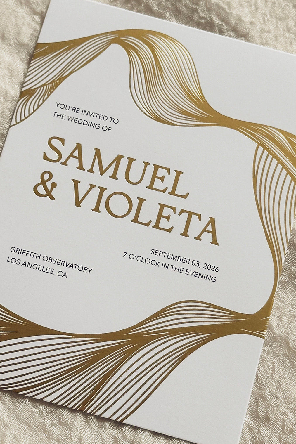 White Invitation with gold foiled flowing lines and names on an ivory background